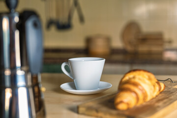 Breakfast in the kitchen with freshly baked croissant and hot cup of coffee