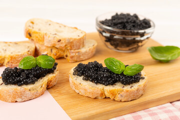 Bread slice with black caviar served on on wooden table