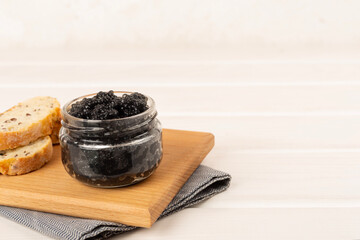 Jar with black caviar on on wooden table