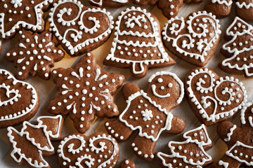 Homemade gingerbread Christmas cookie decorated with white icing on a sheet of baking paper, top view