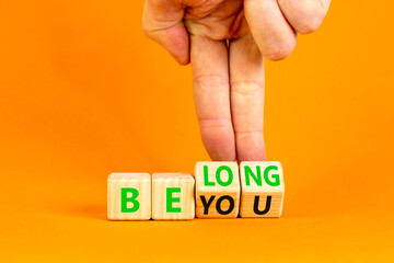 Belonging and belong symbol. Concept words Be you Belong on beautiful wooden block. Beautiful orange background Businessman hand. Business motivational belonging and belong concept. Copy space.