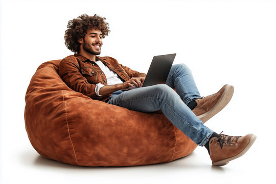 A man is sitting on a bean bag chair and using a laptop. He is smiling and he is enjoying himself. Concept of relaxation and leisure - Powered by Adobe