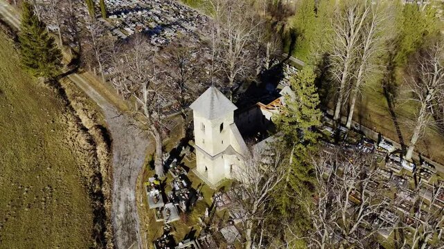 Aerial Drone View of an Old Church in the Middle of a Cemetery in Rural Landscape, Rotating View