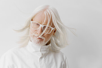 Elderly man with long white hair and glasses, wearing a white outfit, against a white background,...