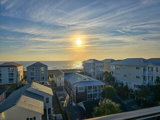 A beautiful sunrise over the Atlantic ocean with homes and condos, lush green trees, a sandy beach...