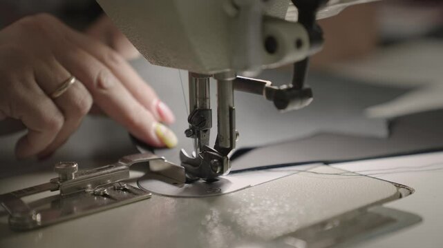 hands seamstress sew product from leather fabric sewing machine. concept female business work home. tailor sews high quality fabric. concept work private leather workshop motion. needle process sewing
