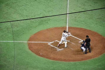 Baseball players in action on a mound, surrounded by green turf, showcasing the intensity and skill of the game. Famous Japanese national sport.