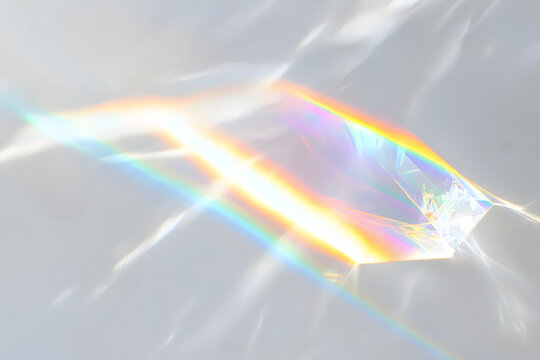 Crystal prism rainbow light refraction texture on white wall background. Organic drop diagonal holographic flare on a white wall. Water shadows for natural light overlay effects