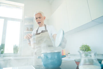 Elderly woman in kitchen cooking delicious meal with enthusiasm and fun