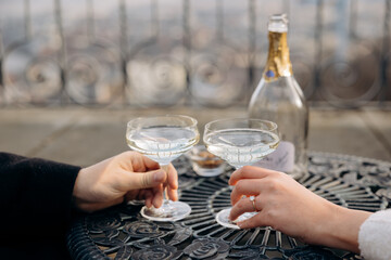 Elegant Hand with Engagement Ring and Champagne Glasses on Ornate Table