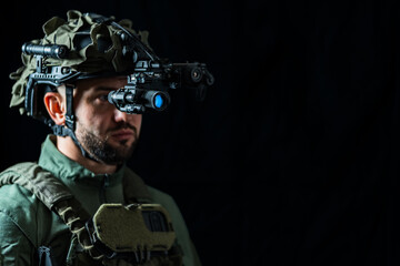 A serviceman using binocular night vision in the darkness. Copy space black background photo.