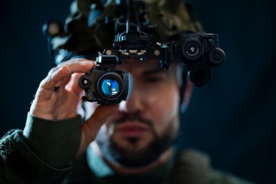 A soldier using binocular night vision in the darkness.