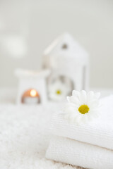 White towels with chamomile flower and aroma lamp, candle on background. Spa therapy, massage salon, romantic relaxation concept. Body care and treatment. Selflove. Copy space.