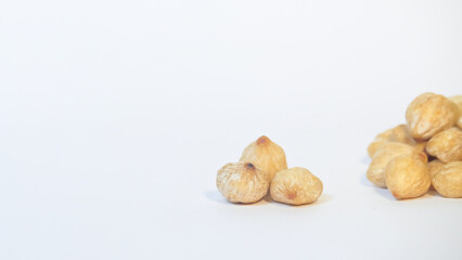Close up of a pile of brown candlenut seeds isolated on white background.Natural candlenut texture background.Copy space for text.Concept of spices.For graphic design or banner background
