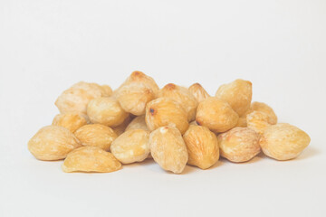 Close up of a pile of brown candlenut seeds isolated on white background.Natural candlenut texture background.Copy space for text.Concept of spices.For graphic design or banner background