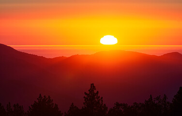 View from Ventana Wilderness, Big Sur, of a sunset on the horizon with bright red glow.