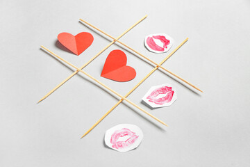 Tic tac toe game with paper hearts and lipstick kiss marks on light background. Valentines Day...
