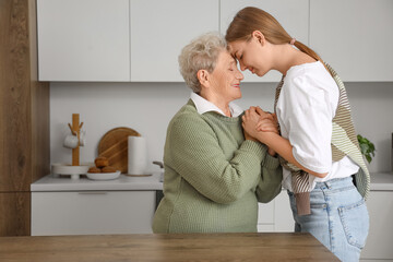 Happy senior woman and her granddaughter in kitchen at home