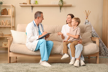 Male pediatrician working with little boy and mother at home