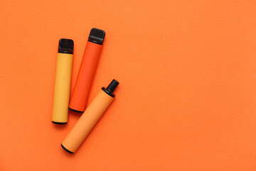 Set of disposable electronic cigarettes on orange background
