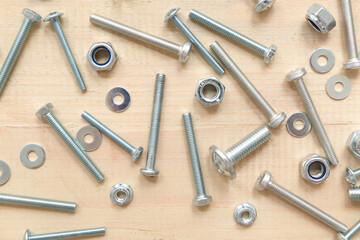 Tap bolts, chrome nuts and washers on wooden background