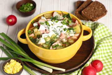 Composition with bowl of tasty okroshka, ingredients and bread on light wooden background
