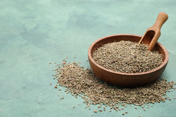 Wooden bowl of dried anise seeds with scoop on green grunge background