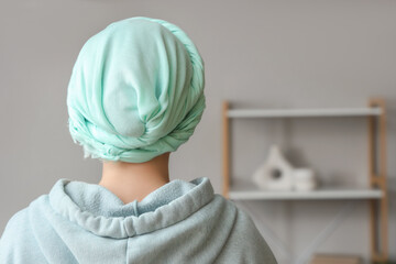 Young woman in headscarf after chemotherapy at home, back view. Cervical Health Awareness Month