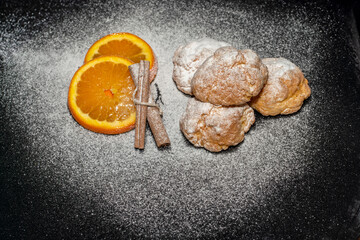 orange cookies and cinnamon powdered sugar on black background kitchen concept