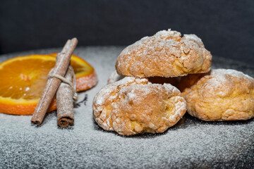 orange cookies and cinnamon powdered sugar on black background kitchen concept