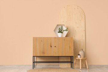 Interior of living room with wooden commode, stool and plant