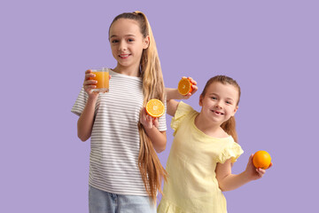 Cute girls with juice and oranges on lilac background