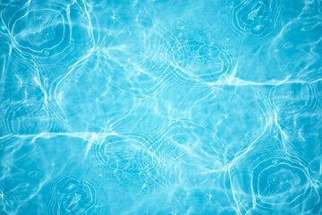 Blue water with ripples on the surface. Defocus blurred transparent blue colored clear calm water surface texture with splashes and bubbles. Water waves with shining pattern texture background.