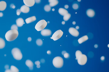 White pills falling on a blue background