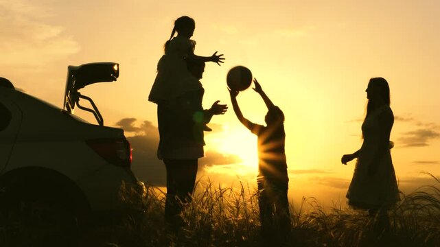 Father mother child play with ball rays sun laugh joyfully. Happy family playing with ball near car sunset. childhood dream trip. kid with parents picnic forest. silhouette happy family with children