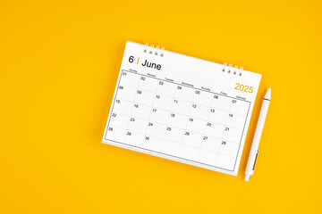 June 2025, Monthly desk calendar for 2025 year and pen on yellow background.