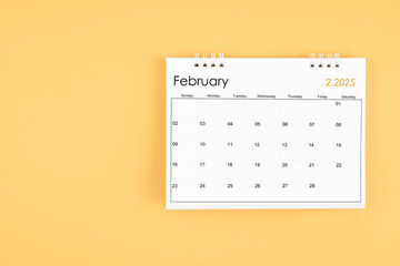 February 2025 desk calendar on yellow color background, position with copy space.