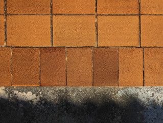 Top view of reddish brown rustic natural stoneware outdoor floor. Classic rough anti-slip matte terracotta ceramic square tiles, rectangular slab border, paving, terrace, porch, patio, pool exterior. 
