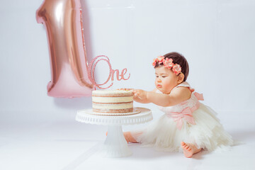 Retrato de una pequeña y alegre cumpleañera con el primer pastel. Comiendo el primer pastel....