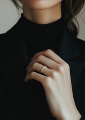 Elegant female hand with minimalist gold ring on black jacket