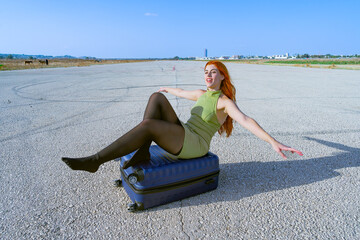 Mujer sentada en una pista de aterrizaje con los brazos abiertos soñando que ya esta en el aire...