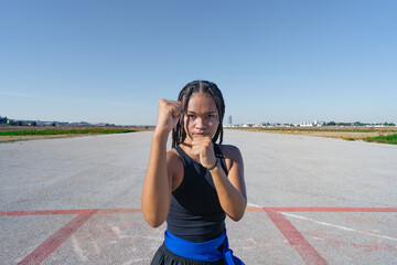 Chica joven luchadora de artes marciales en el paisaje infinito y minimalista de una pista de...