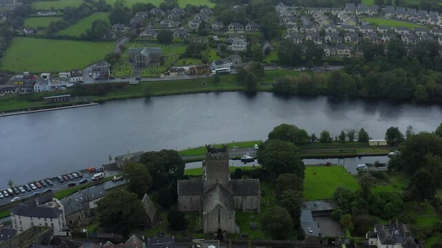 St Flannan's Cathedral, Killaloe, County Clare, Ireland, September 2021. Drone orbits counter clockwise while descending towards the old church on the banks of the River Shannon on a wet overcast day.