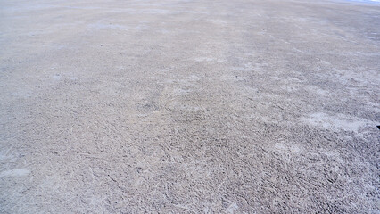 A high-angle close-up shot of the surface of the beach sand which has a texture formed by the life of small crabs within it