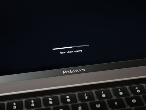 DRESDEN, GERMANY - 30. December 2023: Apple MacBook Pro installing an update. Loading progress bar on the black screen during updating telling the remaining time.