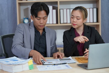 Business partners working together on a new project, analyzing financial documents using a calculator in a meeting. Talking at the desk Analyze data from graphs and charts to solve business problems.