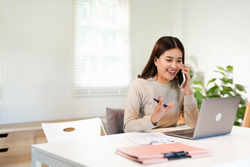 Happy young Asian business woman with a smile using smartphone at the office.