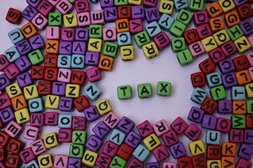 Colorful Alphabet Blocks Spelling 'Tax' on a White Background Surrounded by Letters