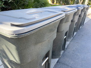 A view of a row of garbage bins along the curb or a local neighborhood.