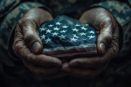 Hands hold a weathered fabric resembling an American flag, evoking memories and patriotism in a solemn setting